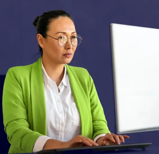 Business professional in green blazer using computer monitor