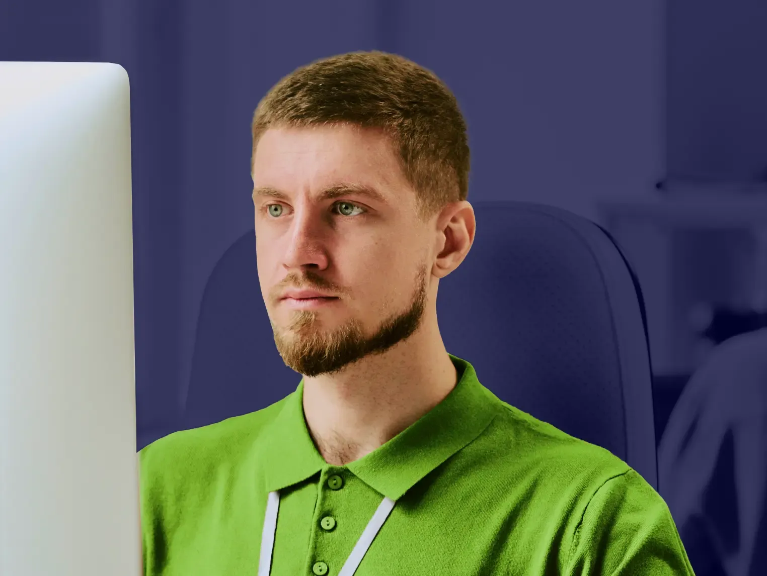 Professional man in green polo with lanyard against office background