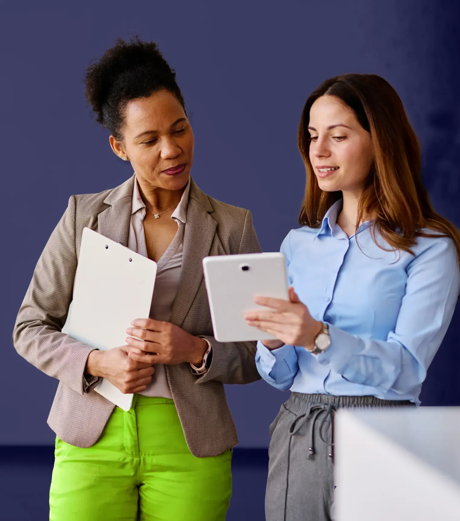 Two professionals reviewing information about the NIS2 Directive cybersecurity legislation on a tablet.