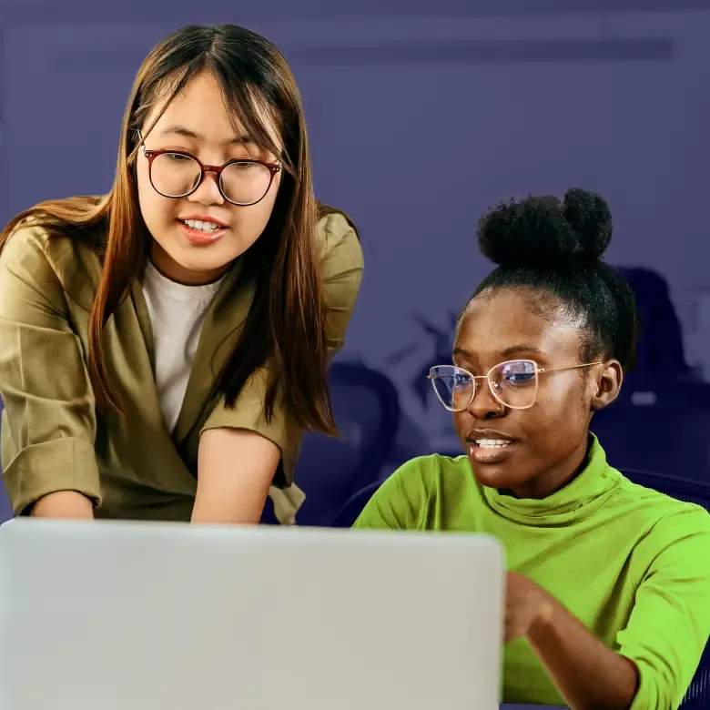 Two women collaborating on laptop during office meeting